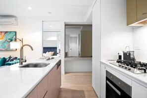 A modern kitchen with a central island, a built-in stove, and a dishwasher. - Lavish 2 Bedroom with Sauna (Melbourne)