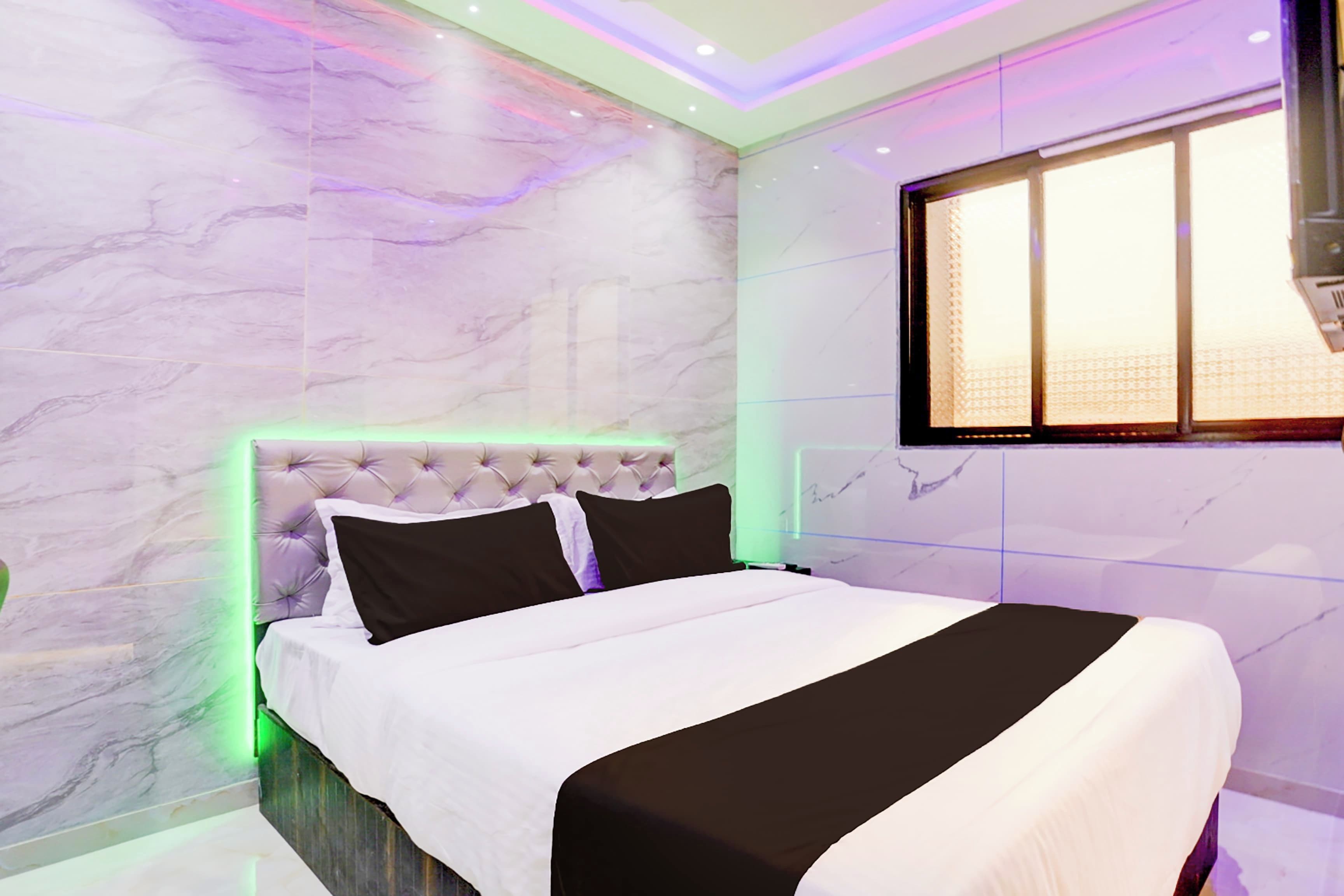 A modern bedroom with a tufted headboard, a large bed, and a window with blinds.