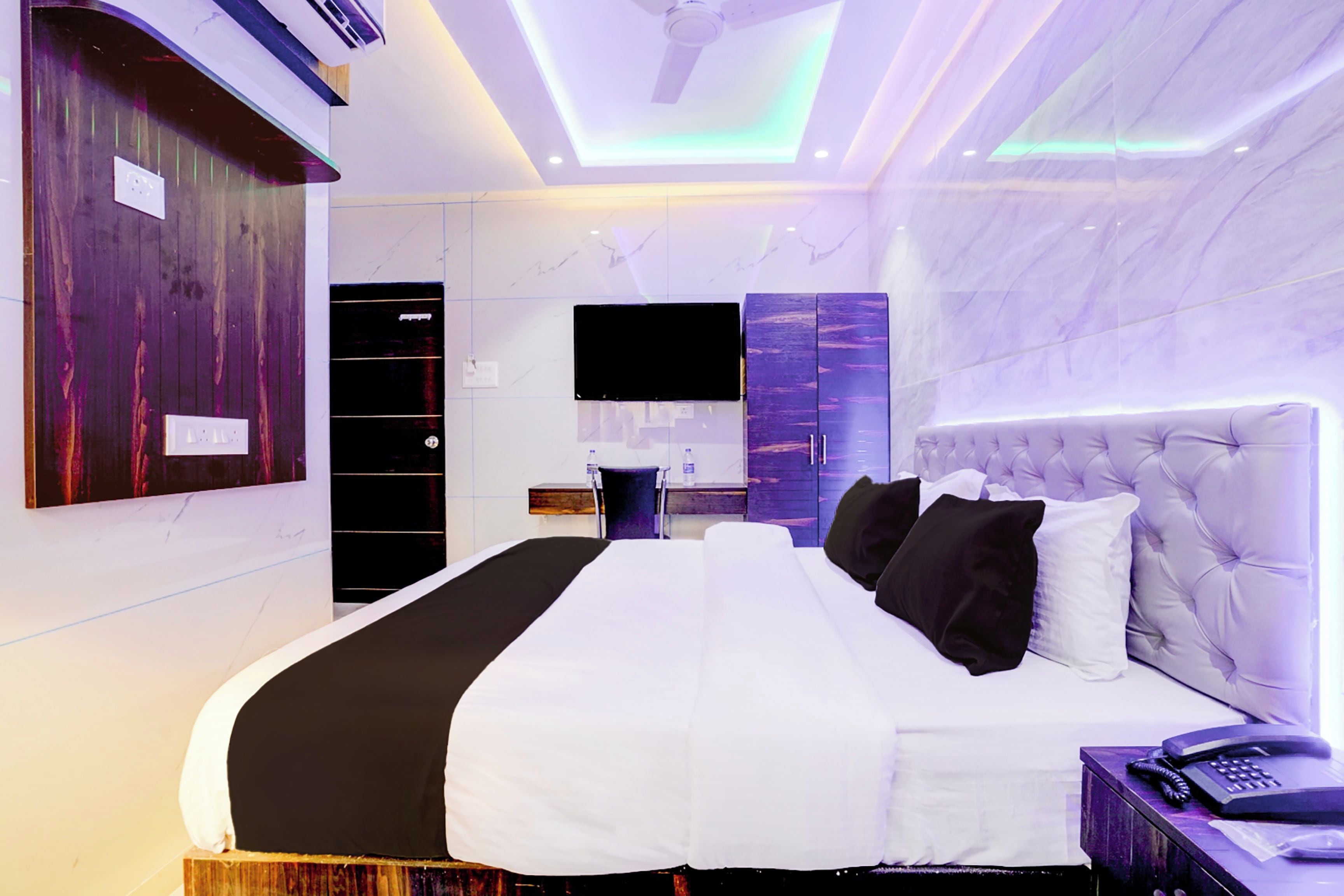A modern hotel room with a large bed, a flat-screen TV mounted on the wall, and a built-in wardrobe.