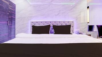 A modern bedroom with a marble headboard, a large bed, and a wardrobe with a purple finish.