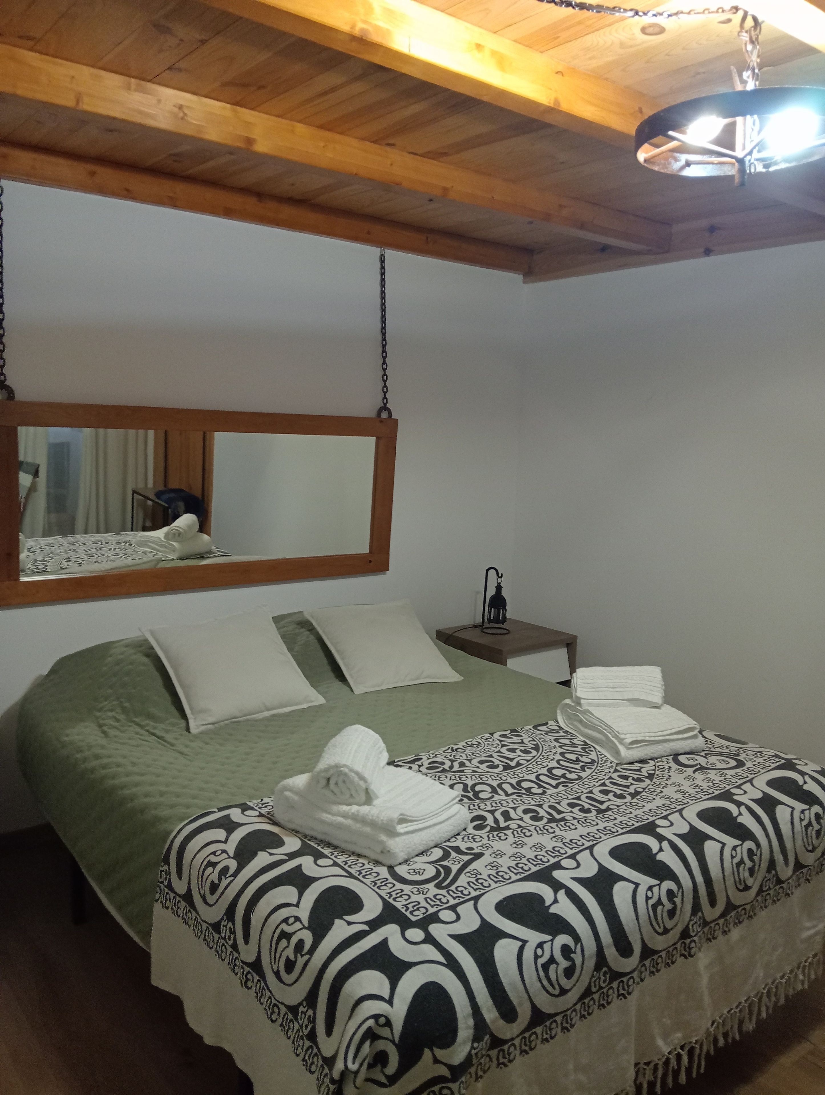 Ein Schlafzimmer mit einem Bett, Kissen, einem Nachttisch mit Lampe und einer Pendelleuchte.