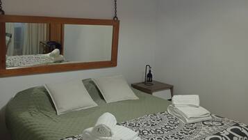 Ein Schlafzimmer mit einem Bett, Kissen, einem Nachttisch mit Lampe und einer Pendelleuchte.
