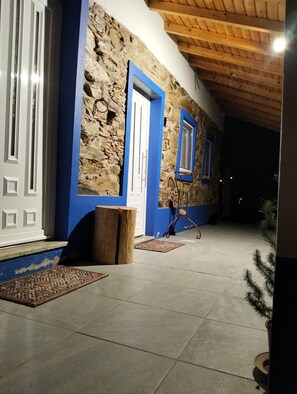 A stone building with blue trim, a wooden bench, and a tiled floor.