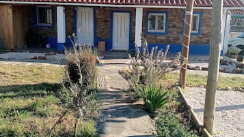 Ein Haus mit rotem Ziegeldach, Steinmauern und einer Veranda mit blauen Fensterrahmen.