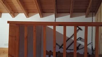 Ein Holzbalkon mit einem Metallgeländer, gestützt von Holzbalken und Ketten.