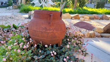 Ein Garten mit einem großen Metalltopf, einer Pergola und verschiedenen Pflanzen.