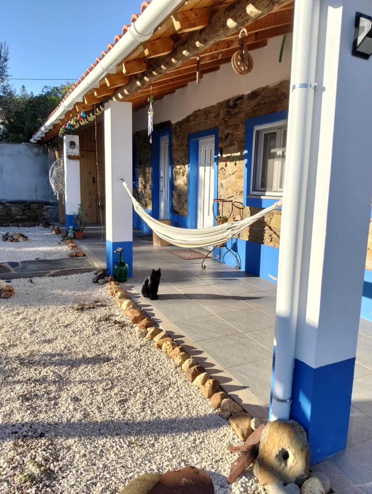 A house with a tiled patio, a hammock, and a cat.