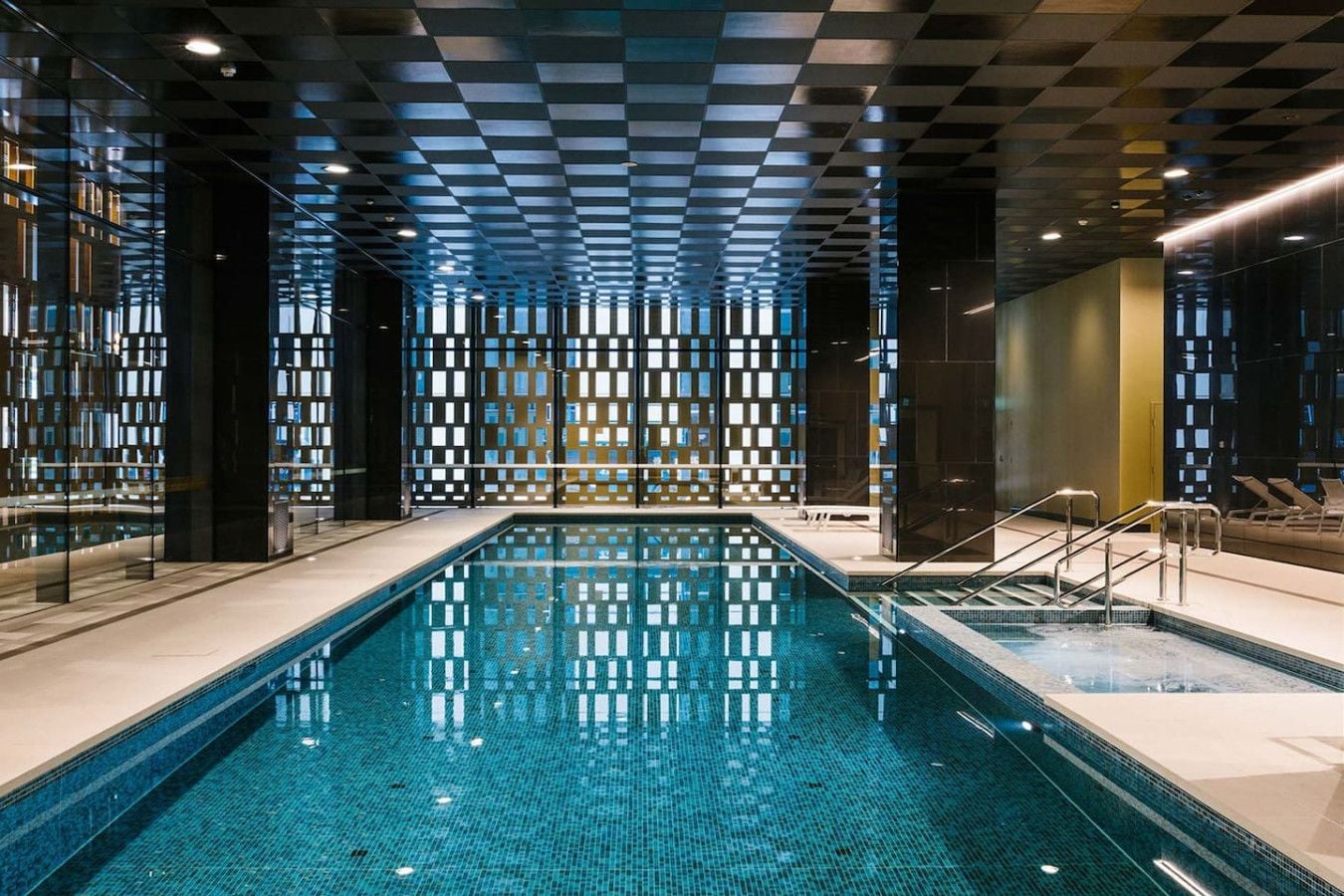 A swimming pool with a checkered ceiling and glass partitions.
