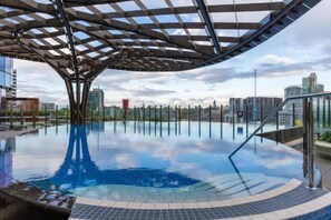 Ein Endlos-Pool mit moderner, architektonischer Überdachung, umgeben von Stadtgebäuden.
