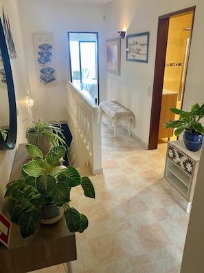 A hallway with a bench, potted plants, and artwork on the walls. - Sea View Dream | Ocean Views, Steps from the Beach, Lagos Algarve (Lagos)