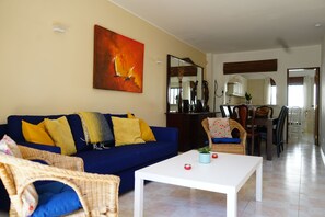 A living room with a blue sofa, a white coffee table, and wicker chairs. - Sea View Dream | Ocean Views, Steps from the Beach, Lagos Algarve (Lagos)