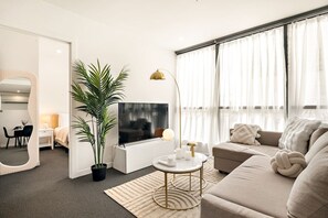 Een moderne woonkamer met een flatscreen televisie, een bank, een salontafel en een potplant.