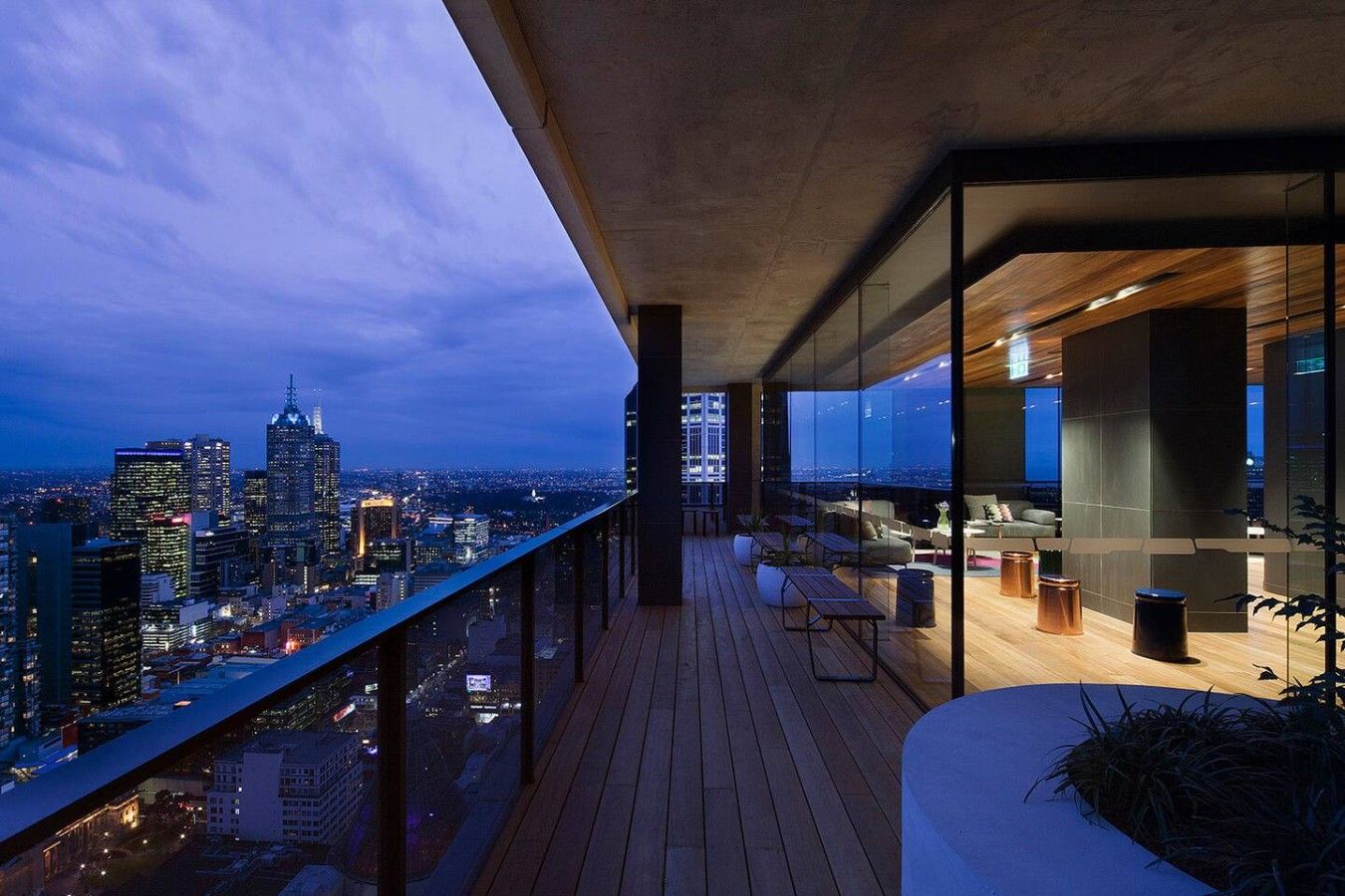Un balcon moderne offrant une vue sur la ville, doté d’un plancher en bois et de mobilier contemporain.