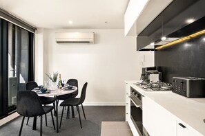 Een moderne keuken met een eethoek, inclusief een tafel gedekt voor vier personen, een inbouwoven en een groot raam dat voor natuurlijk licht zorgt.