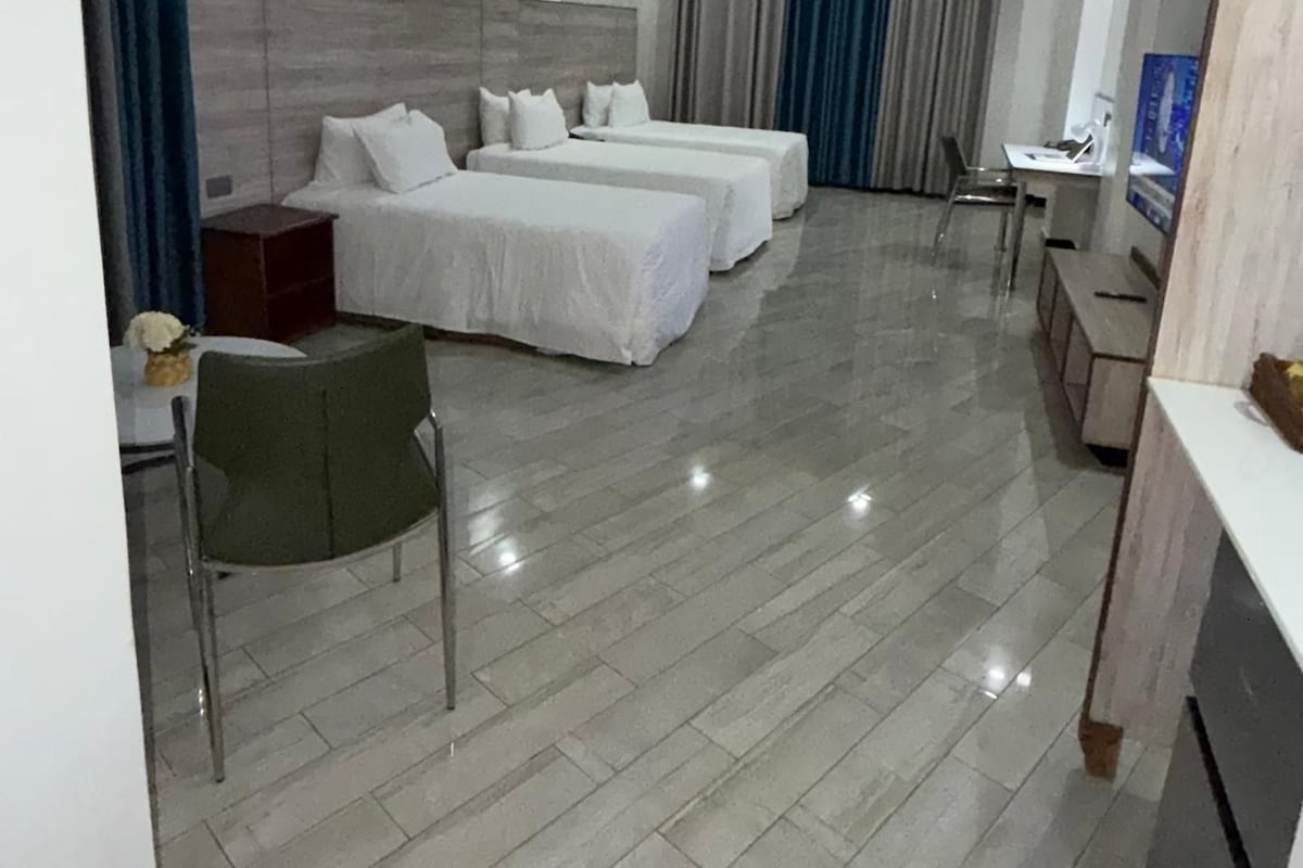 Habitació d'hotel amb dos llits, una escriptori, una cadira i una taula petita.