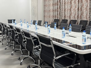 A conference room with a long table, black chairs, and water bottles. - NEXUS RESORTS HOTEL (Kampala)