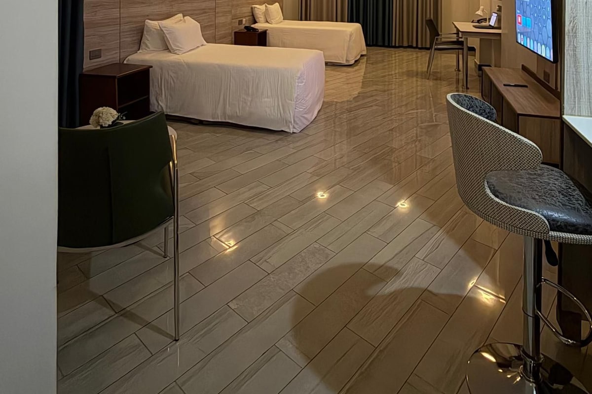 Habitació d'hotel amb dos llits, un escriptori, una cadira i una televisió.