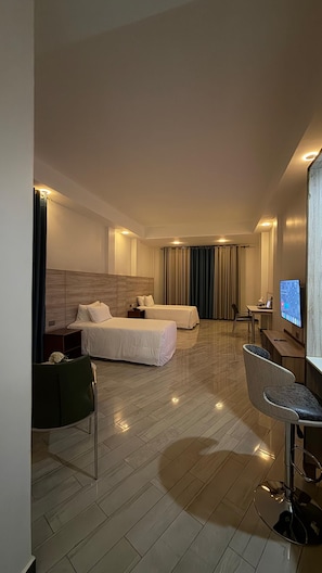 Habitació d'hotel amb dos llits, un escriptori, una cadira i una televisió.
