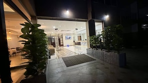Entrada d'un hotel amb una recepció, una zona d'espera i una porta de vidre que dona a l'interior.