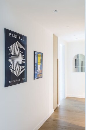A hallway with a framed Bauhaus poster and a New York Times poster on the wall. - New York Style City 3 Bedroom (Melbourne)