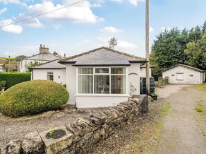 A small, white cottage with a stone wall and a gravel driveway. - Waltergarth (Settle)