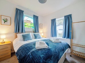 A hotel room with a bed, two bedside tables, a window with curtains, a radiator, and a wall-mounted shelf. - Waltergarth (Settle)