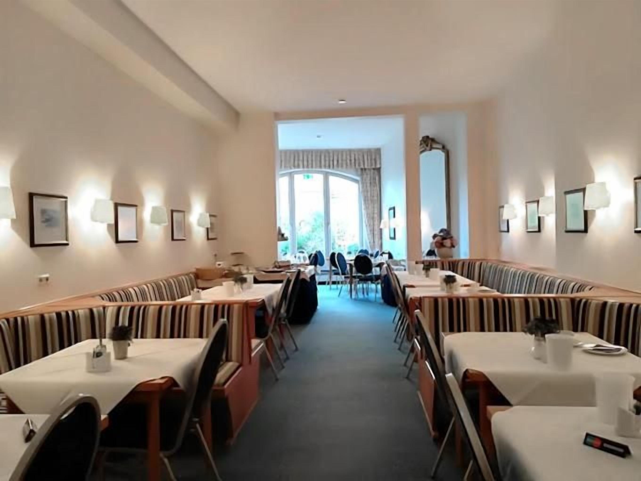 A dining area with booths and tables, framed pictures on the walls, and a view through a large window.