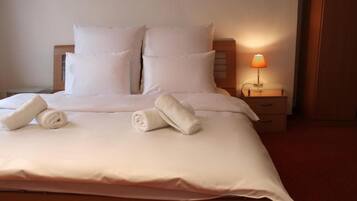 A neatly made bed with pillows and rolled towels, a bedside lamp, and a wooden nightstand.