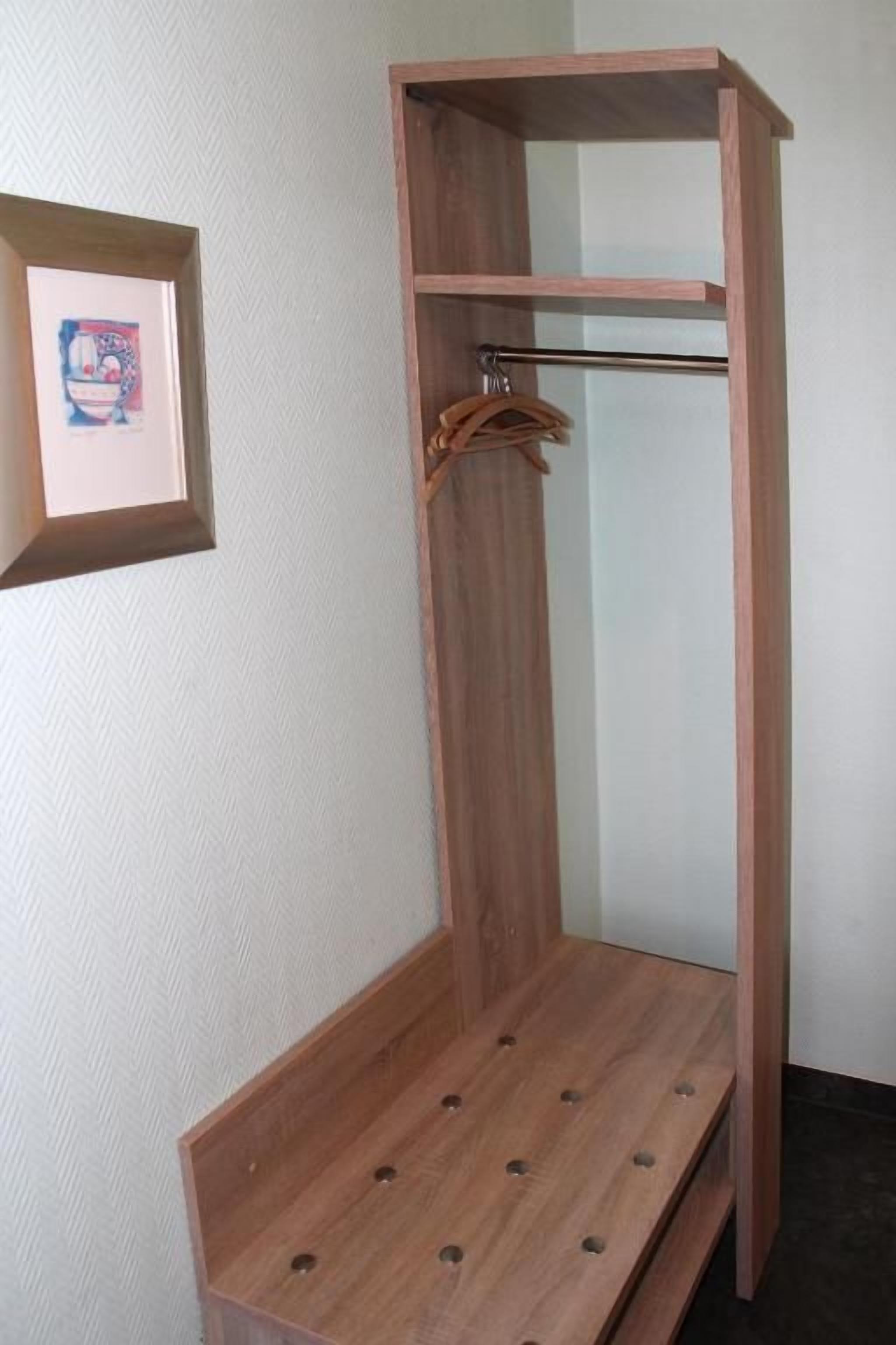 Ein Holfschrank mit Kleiderstange und Ablagefläche.