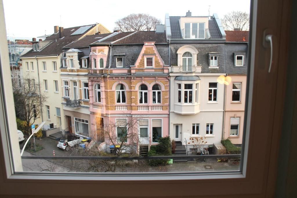 A row of multi-story residential buildings with balconies, a street in front, and a parked car.