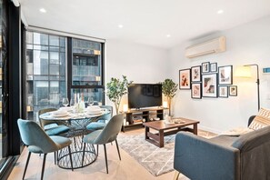 Ein modernes Wohnzimmer mit Essbereich, Flachbildfernseher und großem Fenster.