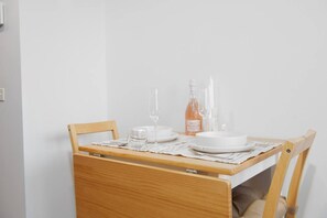A wooden dining table with a white tablecloth, a bottle of water, and clear glasses. - Scandi Oasis with Sky Views (Melbourne)