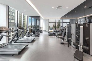 Une salle de sport moderne équipée de tapis de course, d’appareils de musculation et d’un banc.