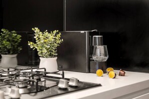 A modern kitchen with a gas stove, a black refrigerator, and a potted plant. - Stylish City 2 Bedroom Gem (Melbourne)