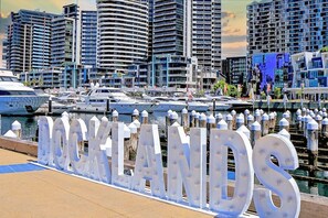 A marina with yachts docked, a large illuminated sign reading 'ROCKLANDS', and modern high-rise buildings in the background. - Marvel Penthouse with Pool (Docklands)