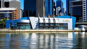 Un bâtiment moderne aux couleurs bleu et blanc, situé près d’une étendue d’eau dont les reflets se mirent.