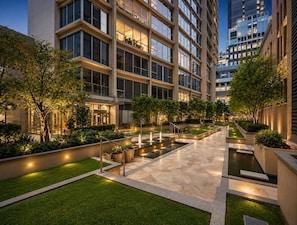 A modern building with multiple floors, outdoor seating areas, and a well-maintained garden with a water feature. - Zen City Retreat with Parking (Melbourne)