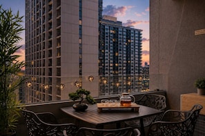 An outdoor seating area with a table, chairs, a bonsai tree, and string lights against a cityscape backdrop. - Zen City Retreat with Parking (Melbourne)