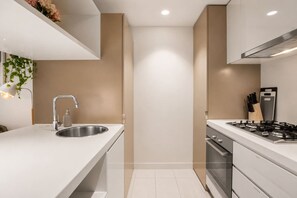 Een moderne keuken met een roestvrijstalen spoelbak, een gasfornuis en een ingebouwde oven.
