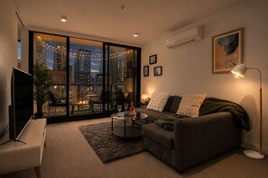 A modern living room with a sofa, coffee table, and a flat-screen TV. - Modern City 2 Bedroom (Melbourne)