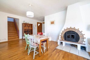 Un comedor con una mesa, sillas, un armario de madera, una chimenea y una escalera.