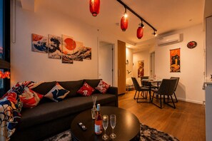 Ein modernes Wohnzimmer mit einer Couch, einem Essbereich mit Stühlen und Kunstwerken an den Wänden.
