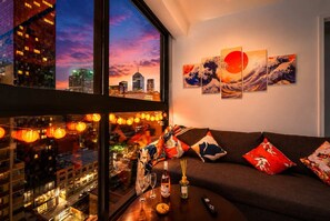 Ein modernes Wohnzimmer mit Blick auf die Stadt, einem großen Fenster und einer Wand mit japanischer Kunst.