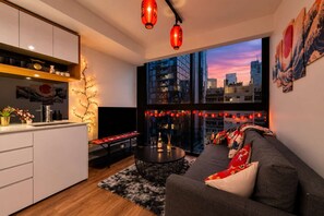 Un saló modern amb un sofà, una taula de dinar i una zona de cuina amb armaris i un televisor.