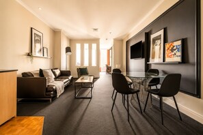 Een moderne woonkamer met een bank, salontafel en een eethoek met stoelen.