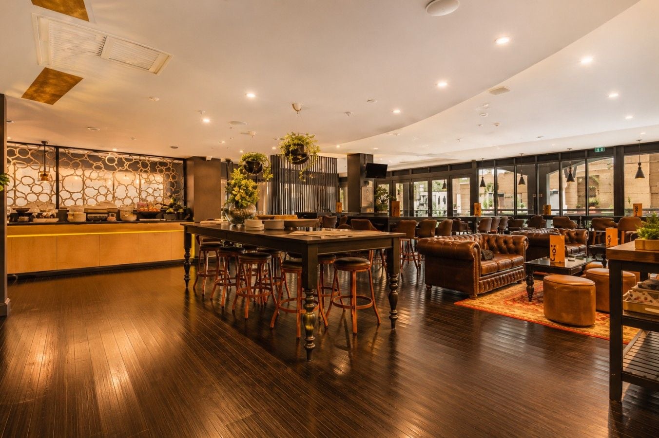 Eine moderne Bar mit einer langen Theke, Hockern und Ledersitzgelegenheiten.