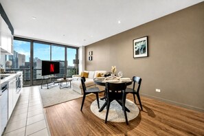 Eine moderne Wohnung mit Essbereich, Küche und großen Fenstern mit Blick auf die Stadt.