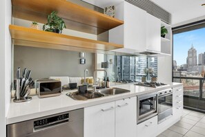 Una cocina moderna con un amplio ventanal, electrodomésticos de acero inoxidable y vistas a la ciudad.