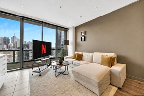 A modern living room with a large window, a flat-screen TV, a sofa, and a coffee table. - River View Southbank Apartment (Melbourne)