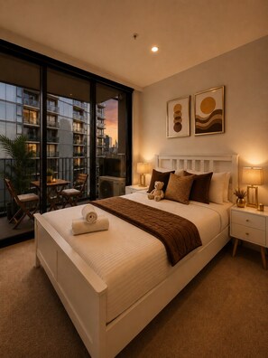 A bedroom with a large bed, bedside tables, a view of a cityscape through a balcony, and artwork on the wall. - Marvel 2 Bedroom with Balcony (Docklands)